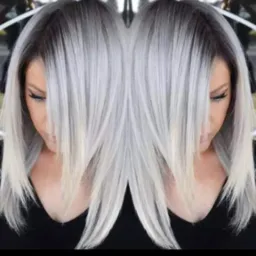 Kobieta z platynowymi włosami ombre, gdzie ciemne odrosty płynnie przechodzą w jasny blond.