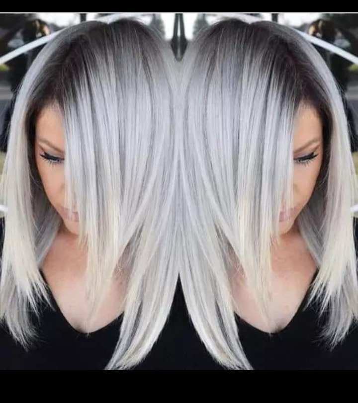 Kobieta z platynowymi włosami ombre, gdzie ciemne odrosty płynnie przechodzą w jasny blond.