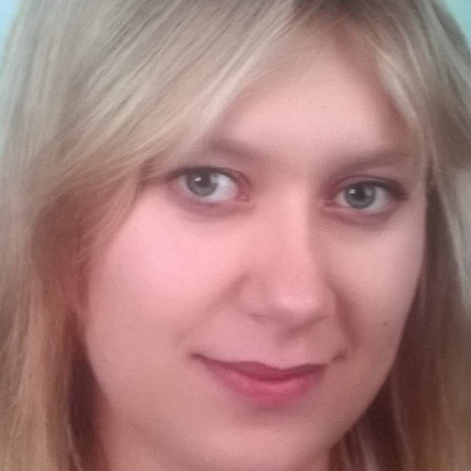 Portret kobiety z blond włosami i delikatnym makijażem, uśmiechająca się bezpośrednio do kamery, z bliska.