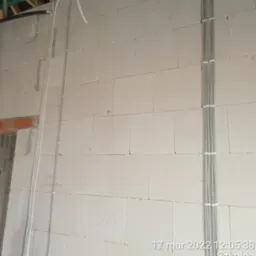 Instalacja elektryczna w surowym stanie: pionowe kable przymocowane do ściany z betonu kom&oacute;rkowego, widoczne otwory instalacyjne, data wykonania zdjęcia w prawym dolnym rogu.