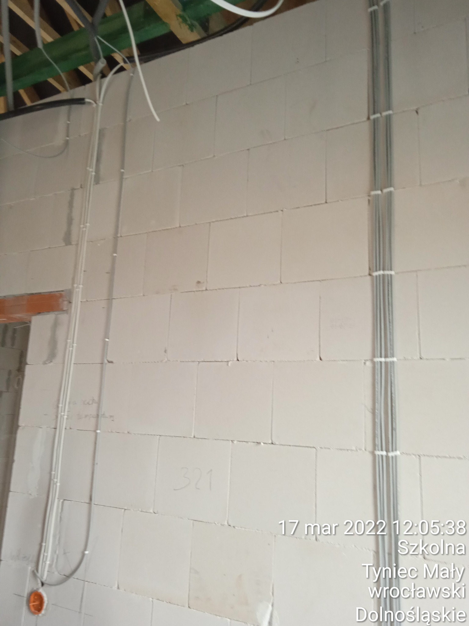 Instalacja elektryczna w surowym stanie: pionowe kable przymocowane do ściany z betonu komórkowego, widoczne otwory instalacyjne, data wykonania zdjęcia w prawym dolnym rogu.