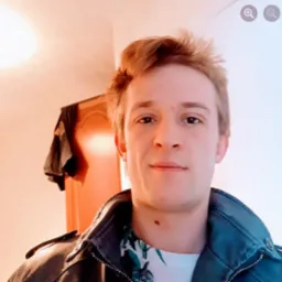 Portret młodego mężczyzny w skórzanej kurtce na tle pokoju z szafą.