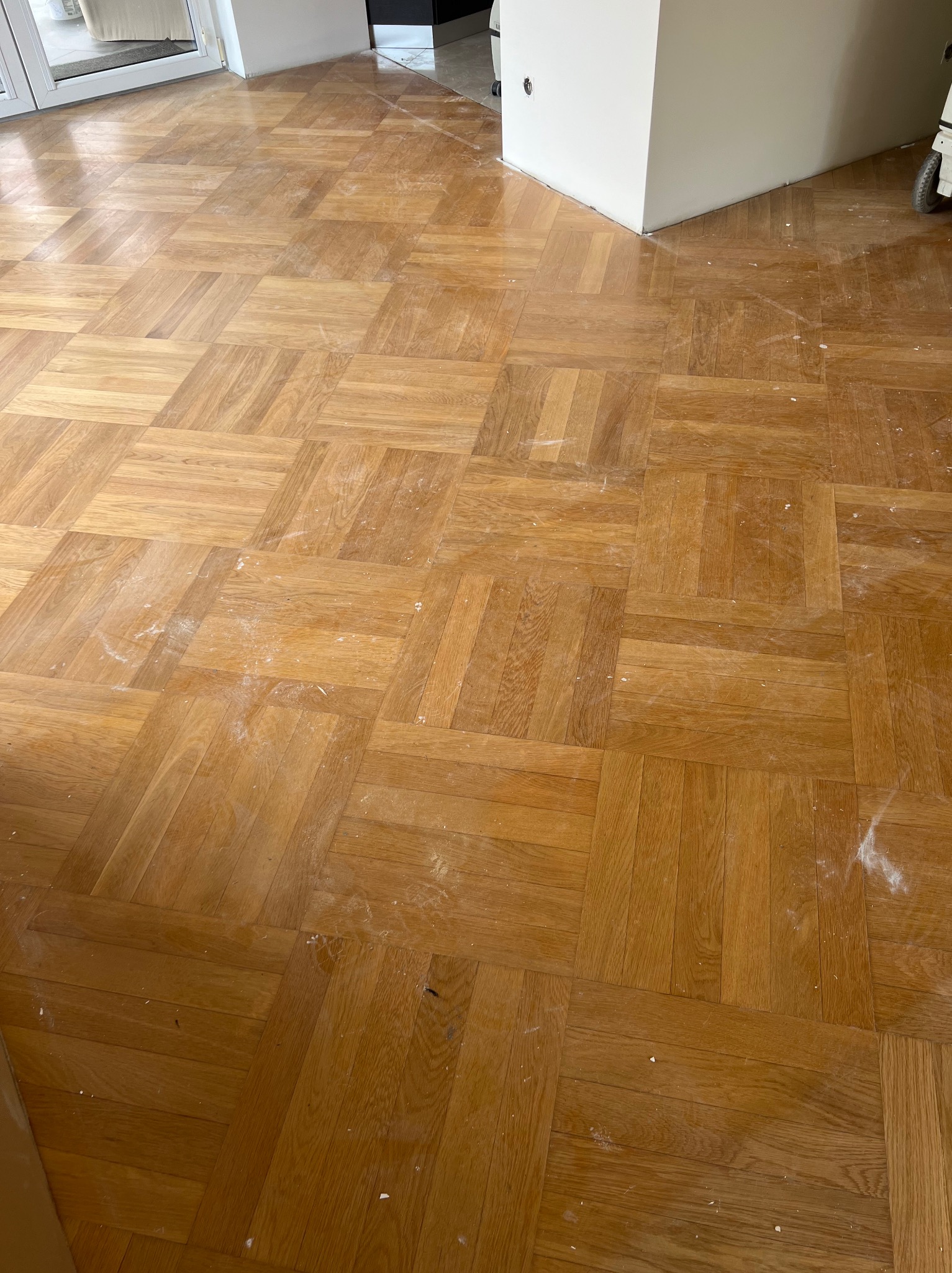 Parkiet w jodełkę po wstępnym szlifowaniu, widoczne ślady pyłu, przygotowany do dalszej obróbki.