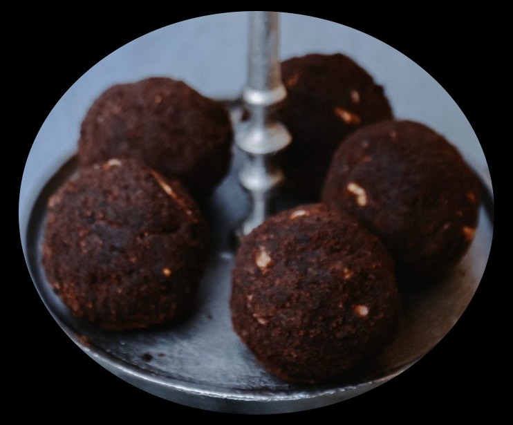 Pięć czekoladowych kulek z orzechami na srebrnej paterze.