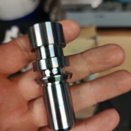 QBIG IRENEUSZ SŁODKOWSKI I WSPÓLNICY SPÓŁKA KOMANDYTOWA - Precyzyjnie obrobiony, błyszczący, metalowy element w dłoni, widoczne ślady obróbki skrawaniem, wielostopniowa konstrukcja.