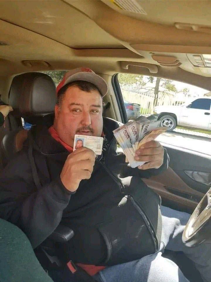 Mężczyzna w samochodzie trzymający w jednej ręce plik banknotów tysiączłotowych, a w drugiej dokument tożsamości ze zdjęciem.