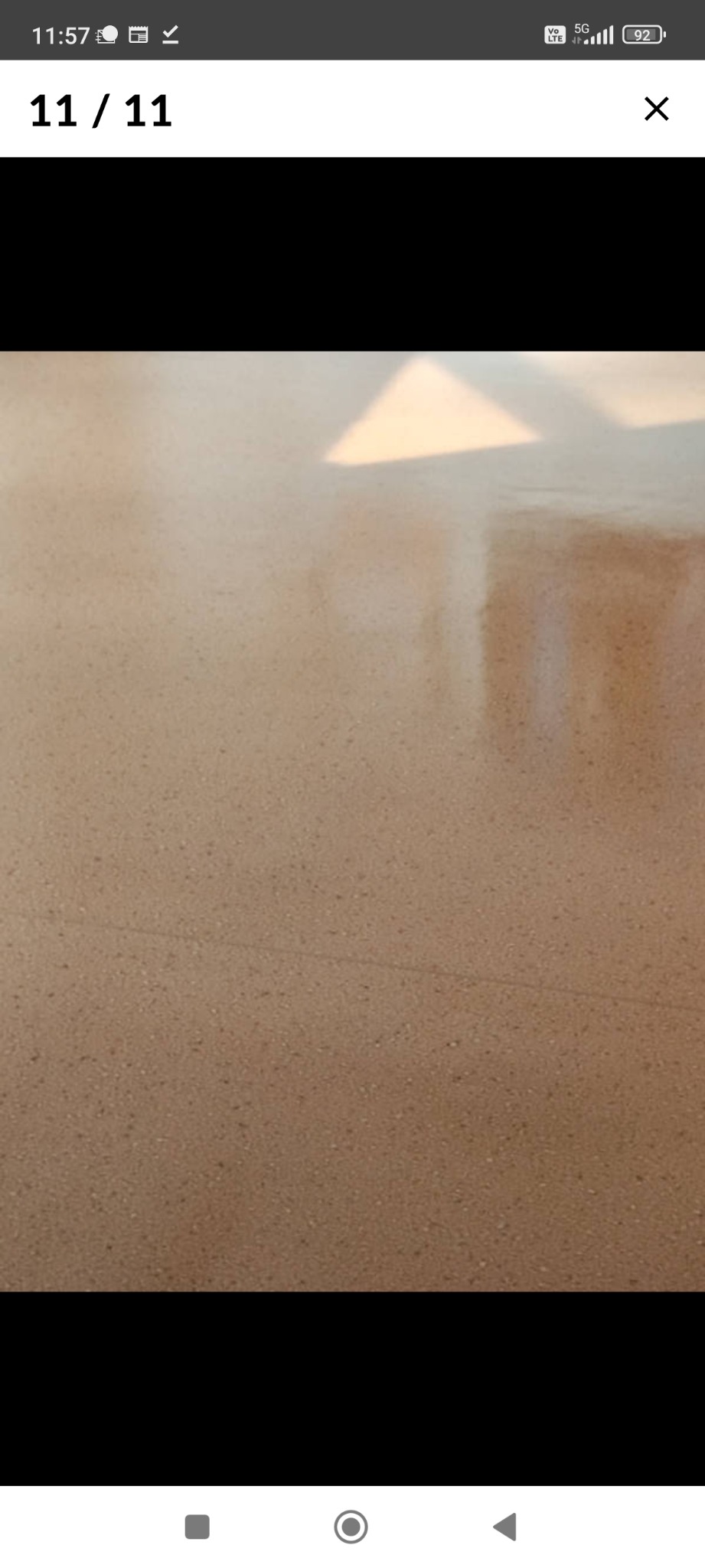 Beżowa, świeżo umyta podłoga z terakoty, z widocznymi refleksami światła słonecznego wpadającego przez okno.