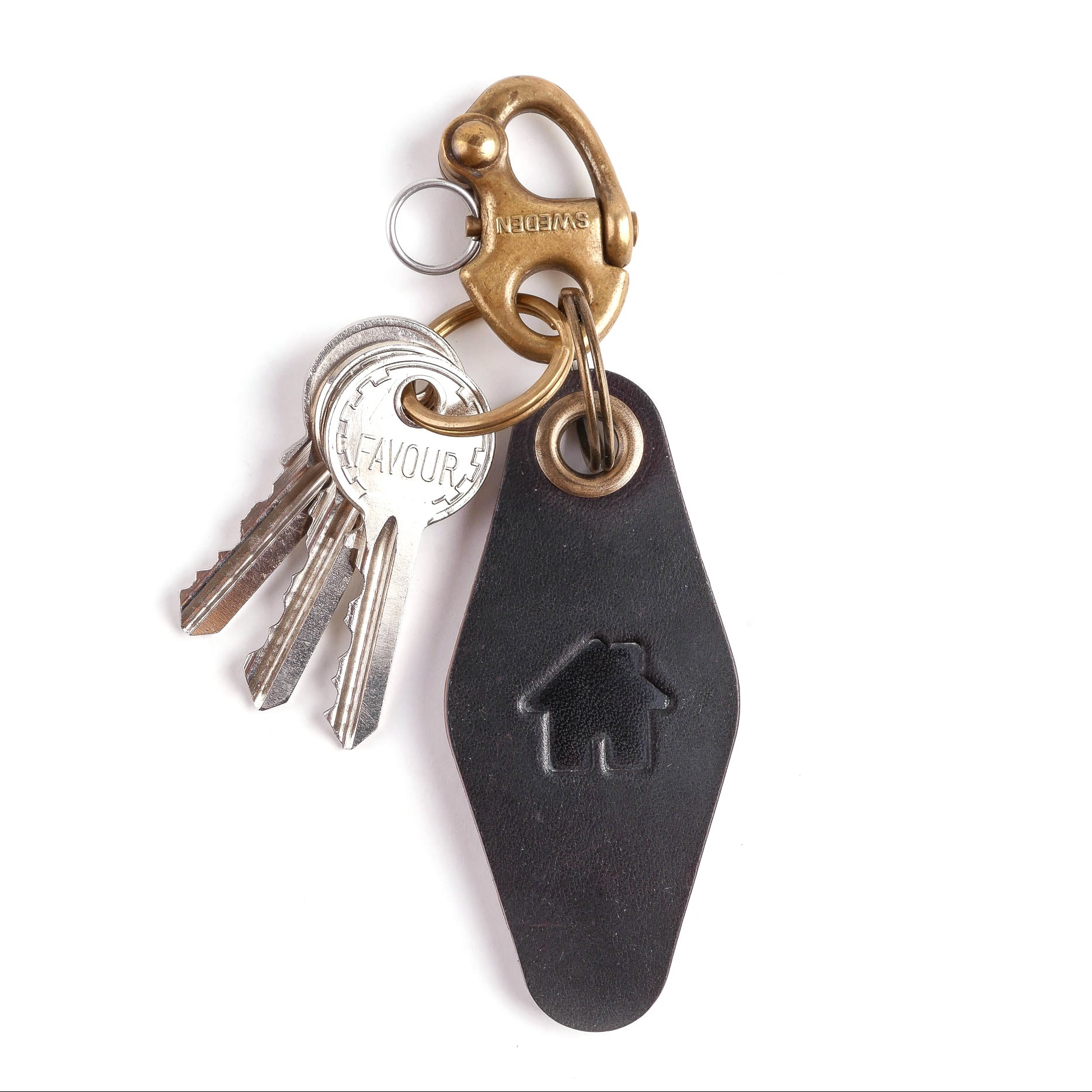 Brelok do kluczy z czarnej skóry z wytłoczonym symbolem domu, zawieszony na mosiężnym karabińczyku z napisem 'SWEDEN' i srebrnych kluczach.