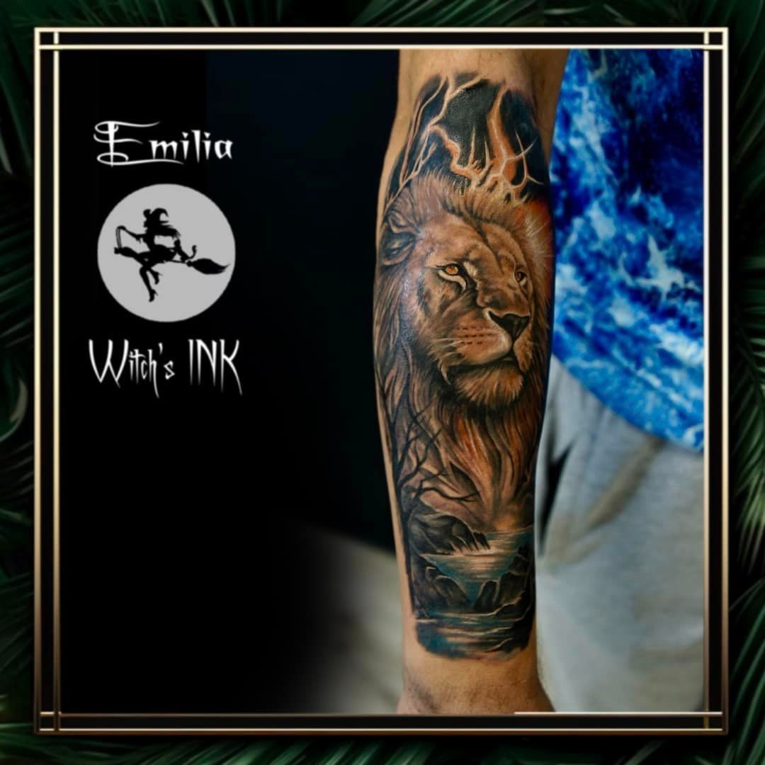 Ramię z realistycznym tatuażem lwa, burzy i krajobrazu wodnego, wykonanym w studiu tatuażu 'Witch's INK' Emilia.