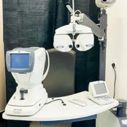 Kompletny zestaw urządzeń diagnostycznych Nidek w gabinecie lekarskim, w tym autorefraktometr i foropter, ustawione na ergonomicznym stole z regulowanym krzesłem.