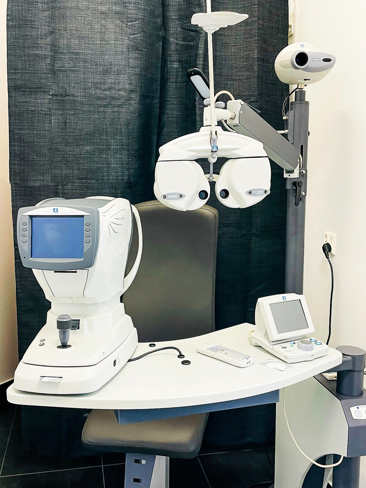 Kompletny zestaw urządzeń diagnostycznych Nidek w gabinecie lekarskim, w tym autorefraktometr i foropter, ustawione na ergonomicznym stole z regulowanym krzesłem.