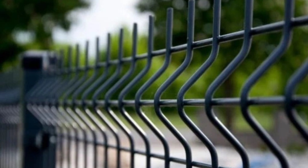 Ciemnoszare przęsło ogrodzenia panelowego z widocznymi mocowaniami słupków, na tle zieleni w Bytomiu.