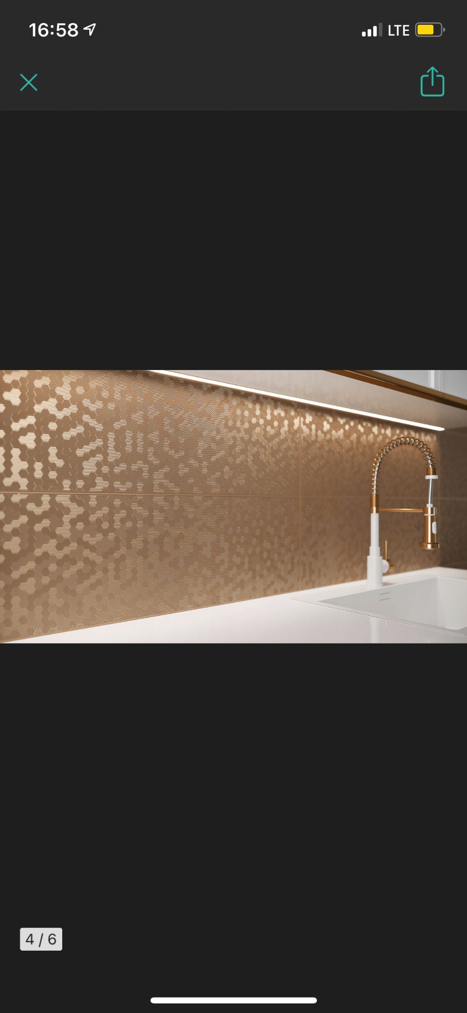 Błyszczące, złote heksagonalne płytki na ścianie nad blatem kuchennym z białym zlewem i złotą baterią, oświetlone listwą LED.