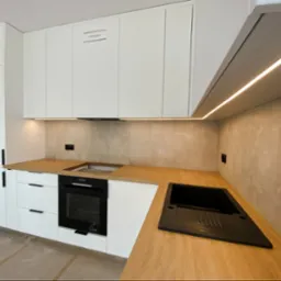 Meble w kolorze biały mat z klasycznym połączeniem ciepłego drewna na blacie całość podświetlone paskiem ledowym.