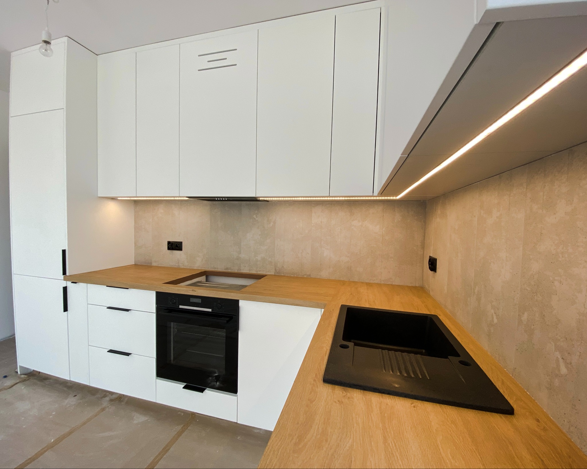 Meble w kolorze biały mat z klasycznym połączeniem ciepłego drewna na blacie całość podświetlone paskiem ledowym.