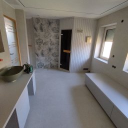 ADMAR ADRIAN MARCISZ - Jasne wnętrze łazienki z umywalką w odcieniach szarości, wzorzystą ścianą i sauną. Widoczne elementy wykończenia i oświetlenie.