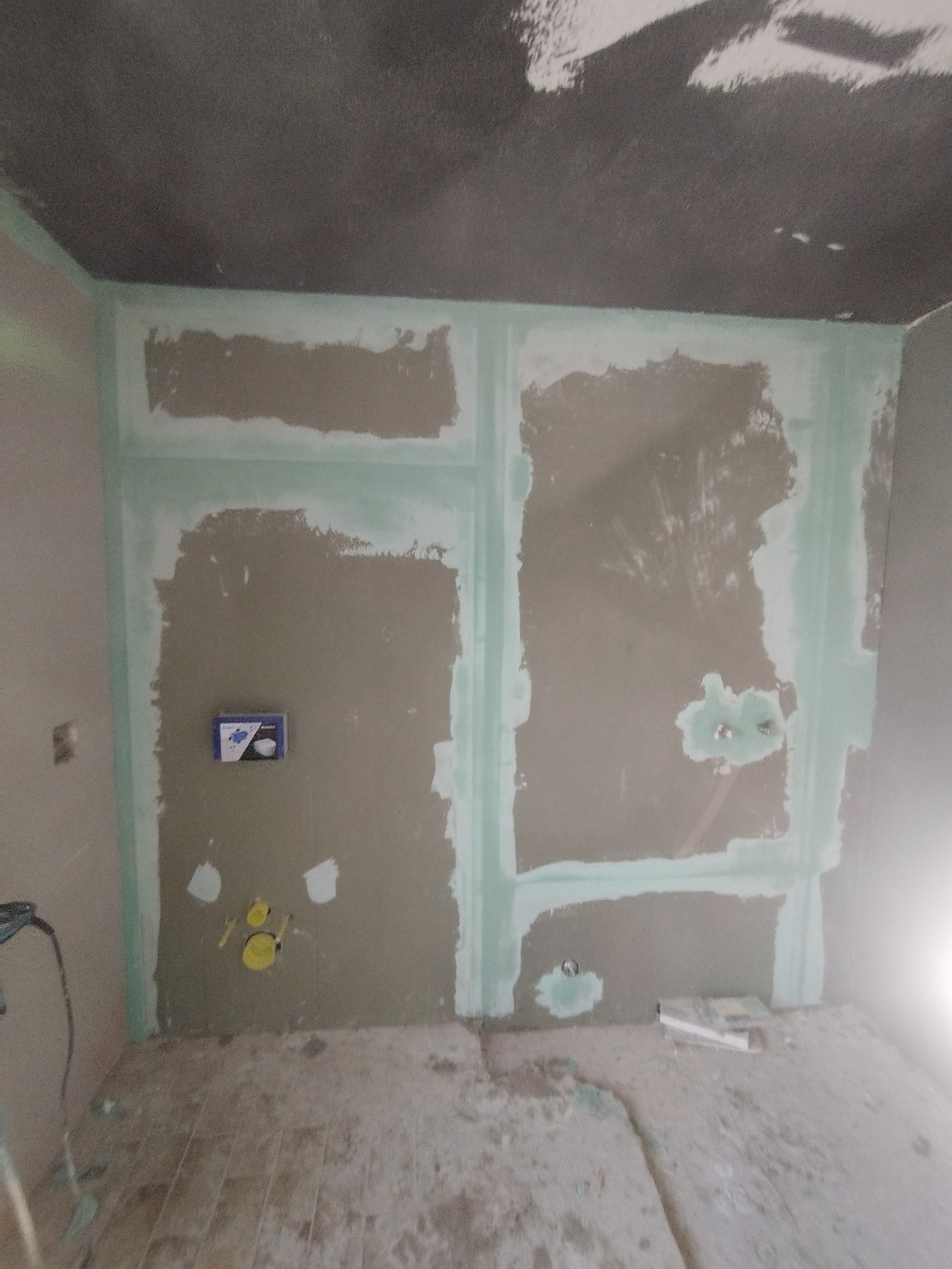 Przygotowanie ścian w łazience do dalszych prac wykończeniowych. Widoczne zaznaczone miejsca pod instalacje i wyrównane ściany z użyciem zielonej taśmy.