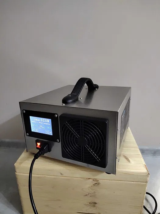 Ozonator kwarcowy Idealozon Platinum Quartz na drewnianej skrzynce, pokazujący wyświetlacz z parametrami i włączony wentylator.