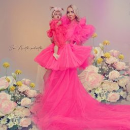 Natallia Shved - Kobieta z blond włosami i mała dziewczynka w różowych, tiulowych sukienkach, otoczone kwiatami na pastelowym tle, podpisane 'So Nata photo'.