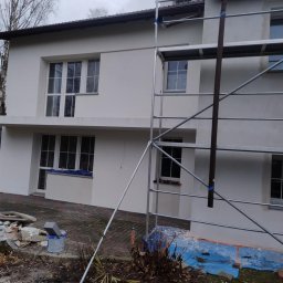 Max Dach - Dwukondygnacyjny dom z rusztowaniem, po świeżym malowaniu elewacji na jasny kolor. Widoczne detale wykończeniowe i przygotowania do dalszych prac.