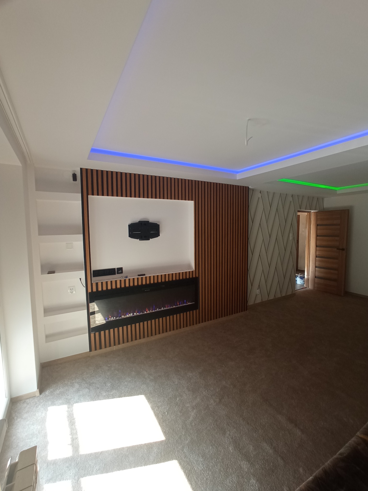 Nowoczesne wykończenie wnętrza w Piotrkowie Trybunalskim: ściana z lamelami, elektryczny kominek, podświetlany sufit i wzorzysta tapeta. Minimalistyczny design.