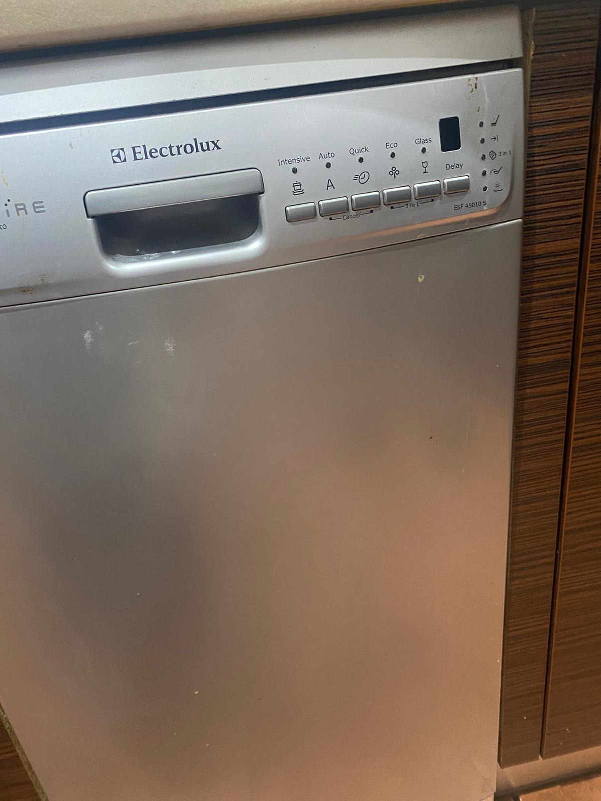 Frontalny widok srebrnej zmywarki Electrolux ESF 45010 S z widocznymi panelami sterowania i drobnymi zabrudzeniami na obudowie.