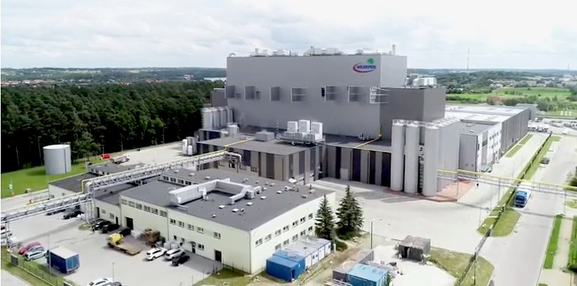 Widok z lotu ptaka na zakład produkcyjny SM Mlekpol w Mrągowie, z widocznymi instalacjami zewnętrznymi, rurociągami i systemami wentylacyjnymi na dachu.