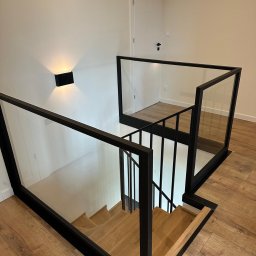 PRO-SPAW Bartosz Białas - Nowoczesne schody z drewnianymi stopniami i balustradami szklanymi w czarnej ramie w Lubcz Wielki. Minimalistyczny design, widok z góry.