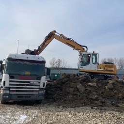 Mariusz Ślęzak Sklep Spożywczo-Przemysłowy - Żółto-biała koparka Liebherr nabiera ziemię na ciężarówkę Scania na tle placu budowy z widocznymi drzewami i błękitnym niebem.