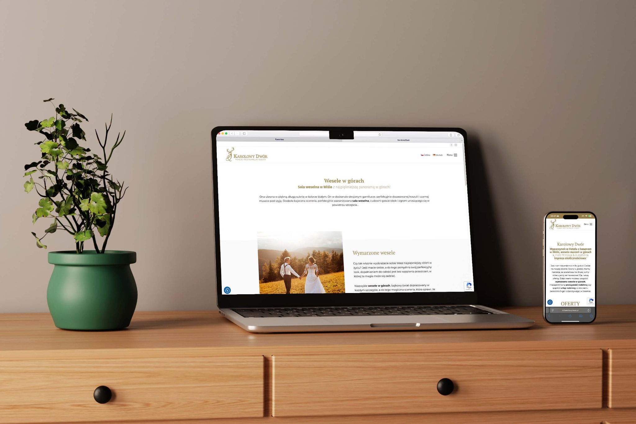 Strona internetowa Karlowy Dwor na laptopie i smartfonie, prezentująca ofertę wesel w górach. Roślina doniczkowa obok, drewniane biurko.