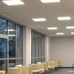 Hallway with suspended ceiling and evenly spaced square LED panel lights, large windows reflecting trees, and waiting area seating.