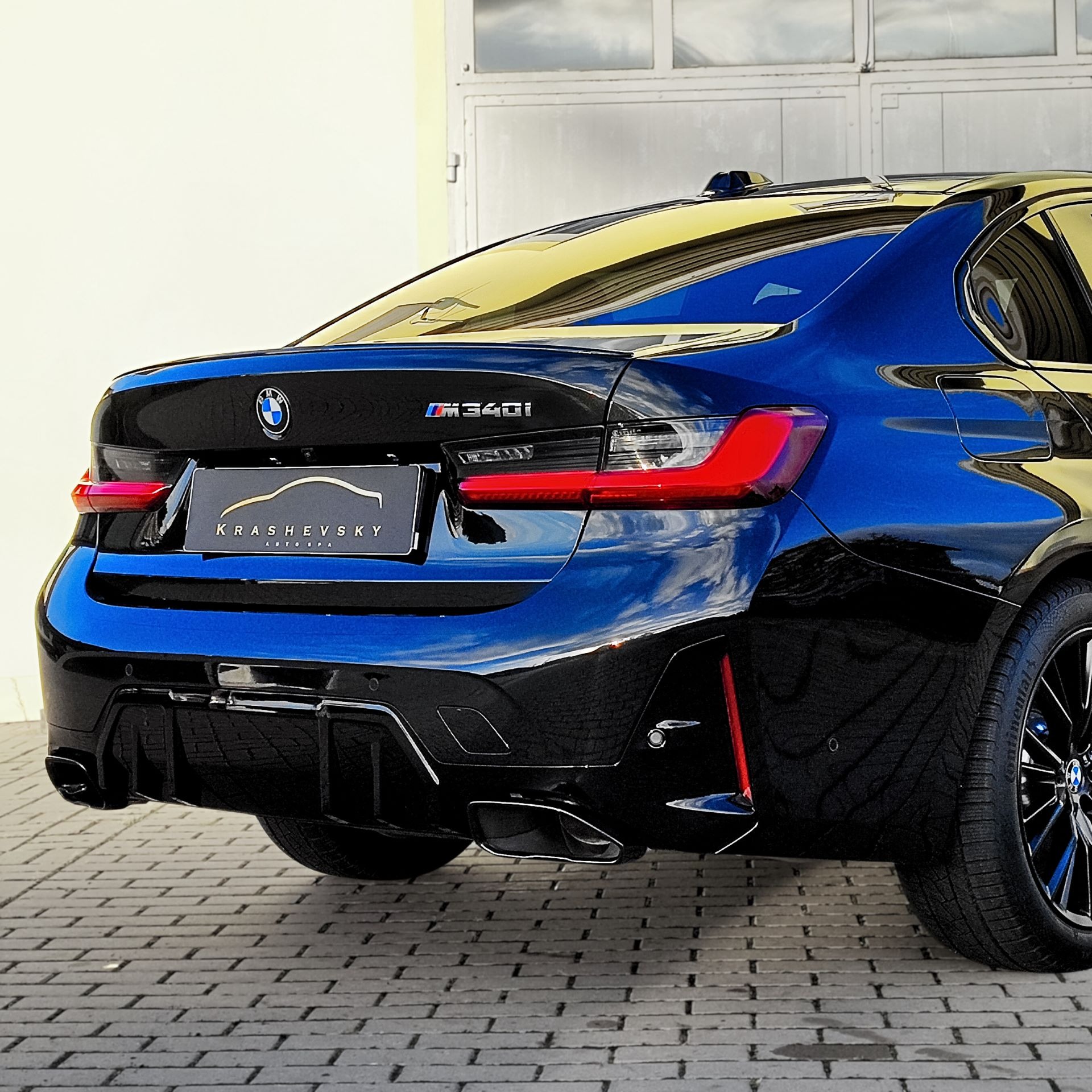 Błyszczący, granatowo-czarny BMW M340i po detailingu w Sierpcu, z widocznym logo Krashevsky Auto Spa na tylnej klapie, odbijający niebo w lakierze.
