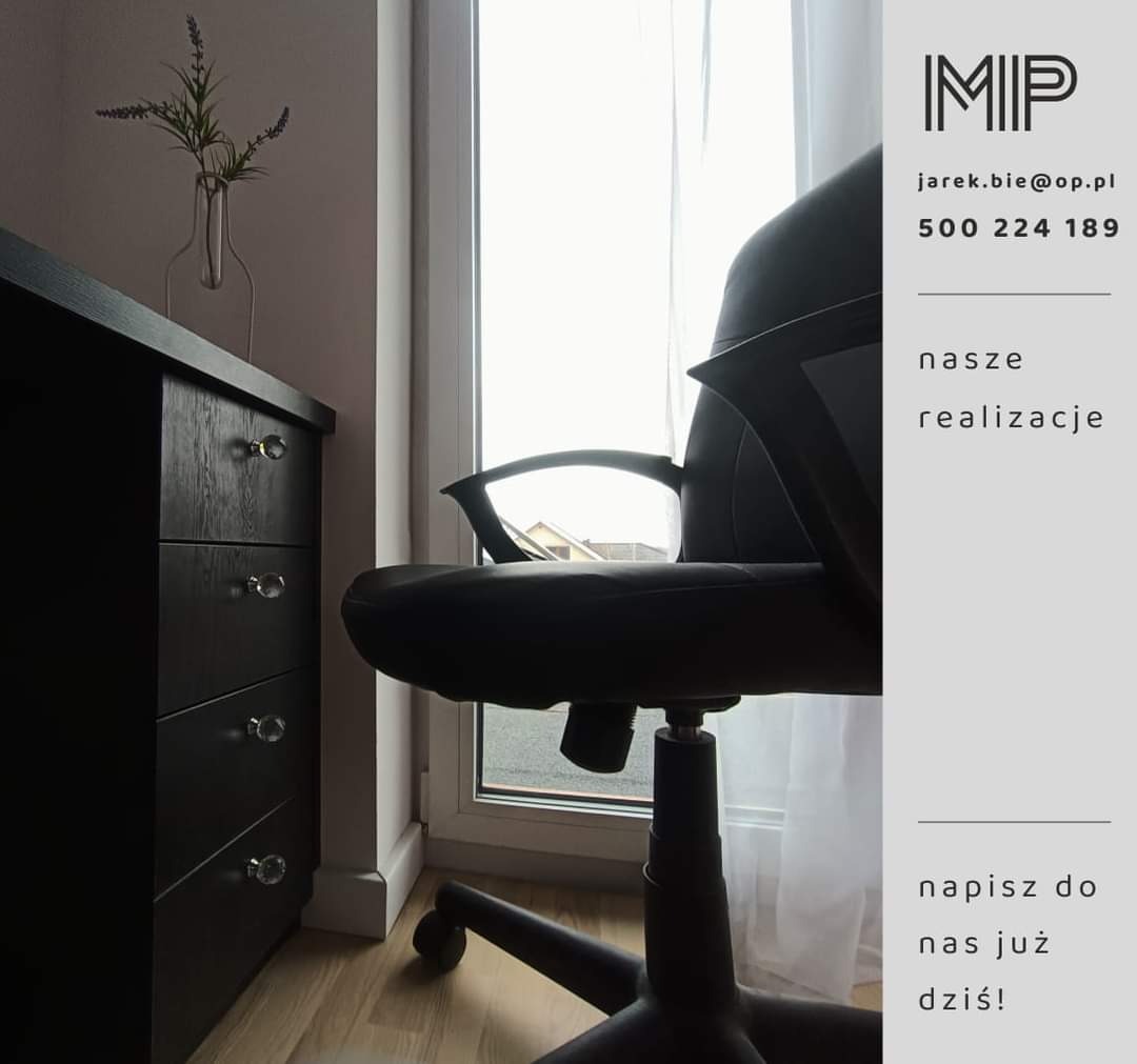 Ciemna komoda z czterema szufladami i kryształowymi gałkami, obok czarne krzesło biurowe na tle okna.