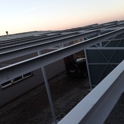 MS STEEL CONSTRUCTION SPÓŁKA Z OGRANICZONĄ ODPOWIEDZIALNOŚCIĄ - Konstrukcja stalowa z profili zamkniętych, tworząca zadaszenie nad podjazdem, widok z góry na samochód zaparkowany pod konstrukcją.