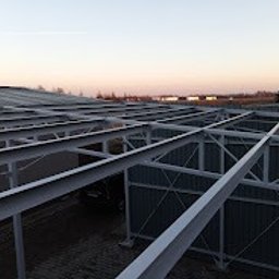 MS STEEL CONSTRUCTION SPÓŁKA Z OGRANICZONĄ ODPOWIEDZIALNOŚCIĄ - Konstrukcja stalowa z profili zamkniętych, widok z góry na szary dach i oddalony horyzont o zmierzchu.