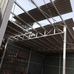 MS STEEL CONSTRUCTION SPÓŁKA Z OGRANICZONĄ ODPOWIEDZIALNOŚCIĄ - Konstrukcja stalowa z blachy falistej w trakcie montażu, widoczne rusztowania i elementy mocujące.