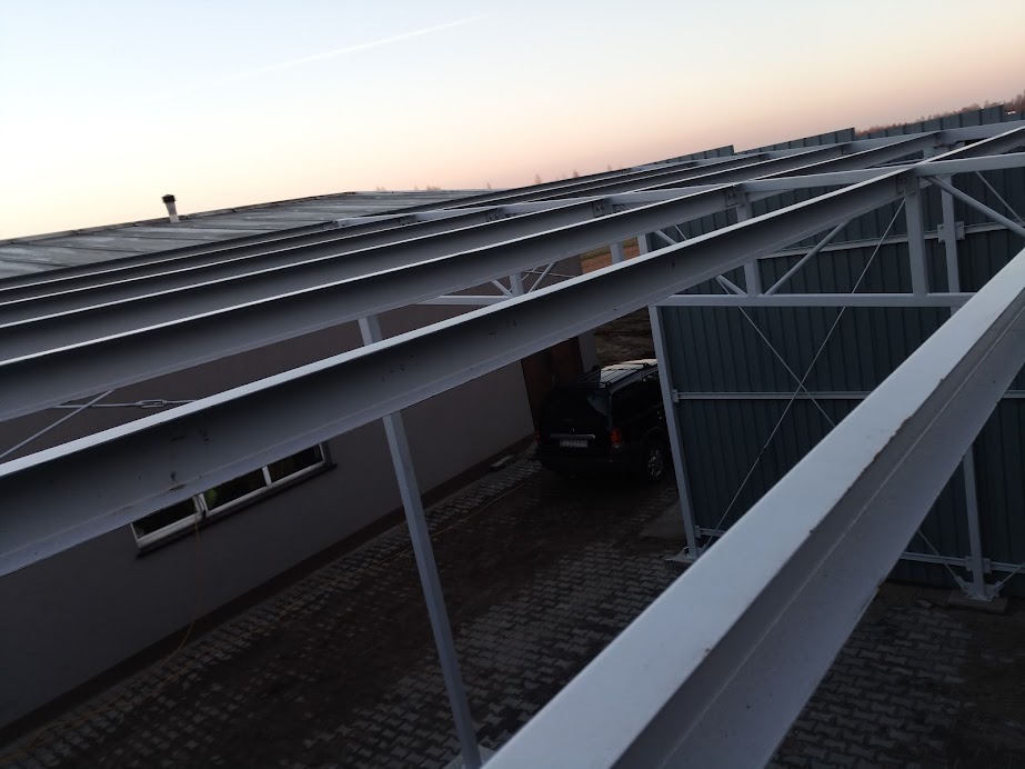 Konstrukcja stalowa z profili zamkniętych, tworząca zadaszenie nad podjazdem, widok z góry na samochód zaparkowany pod konstrukcją.