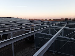 Konstrukcja stalowa z profili zamkniętych, widok z góry na szary dach i oddalony horyzont o zmierzchu.