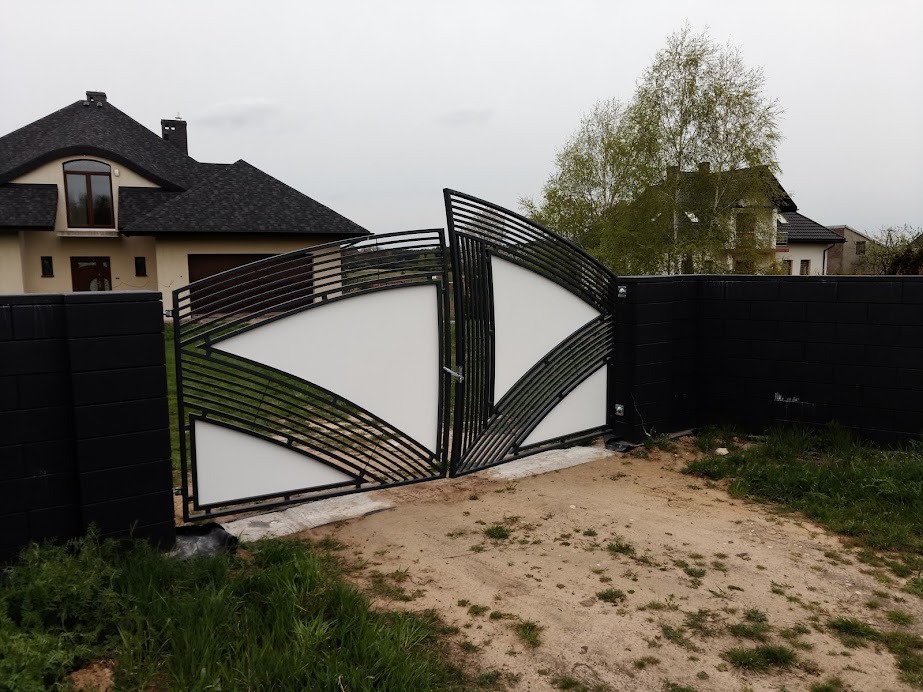 Nowoczesna, dwuskrzydłowa brama wjazdowa z metalowymi elementami i białymi panelami, zamontowana w Krakowie, otoczona czarnym murem z cegły.