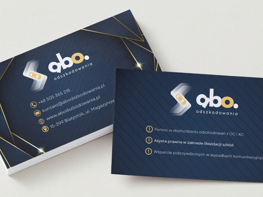 Dwie wizytówki firmy odszkodowawczej z granatowym tłem, logo z symbolem samochodu i danymi kontaktowymi, ułożone na jasnym tle.