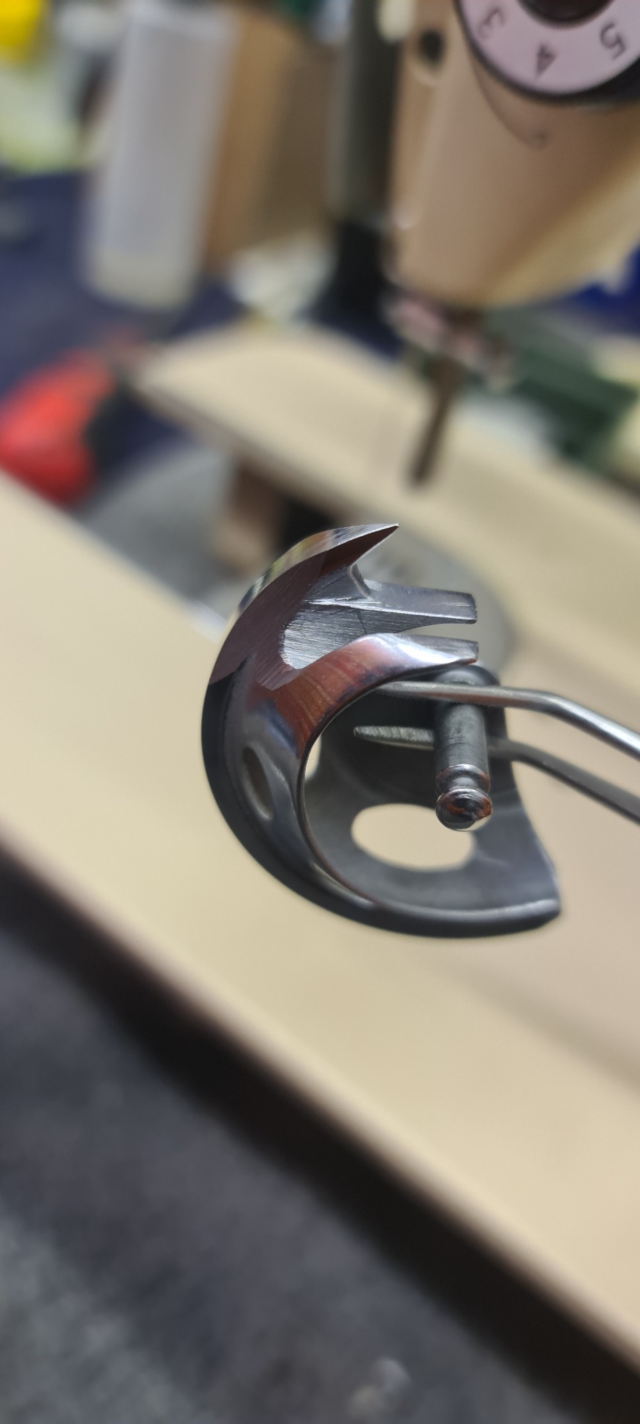 Detail ujęcia mechanizmu chwytacza nici w maszynie do szycia, widoczne ślady użytkowania i drobne zarysowania na metalowej powierzchni.