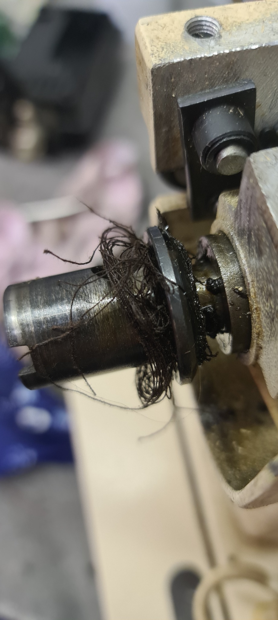 Zablokowany mechanizm maszyny szwalniczej w Śremie, owinięty nitkami i brudem, wymagający pilnej interwencji serwisowej.