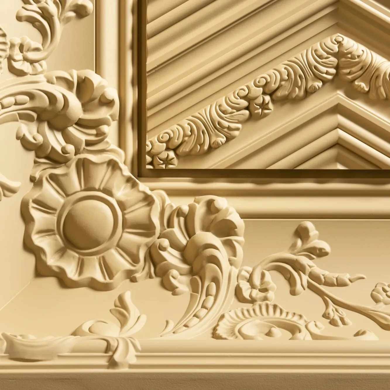Detal dekoracyjny z gipsowych sztukaterii w odcieniach beżu, przedstawiający kwiatowe i geometryczne ornamenty.