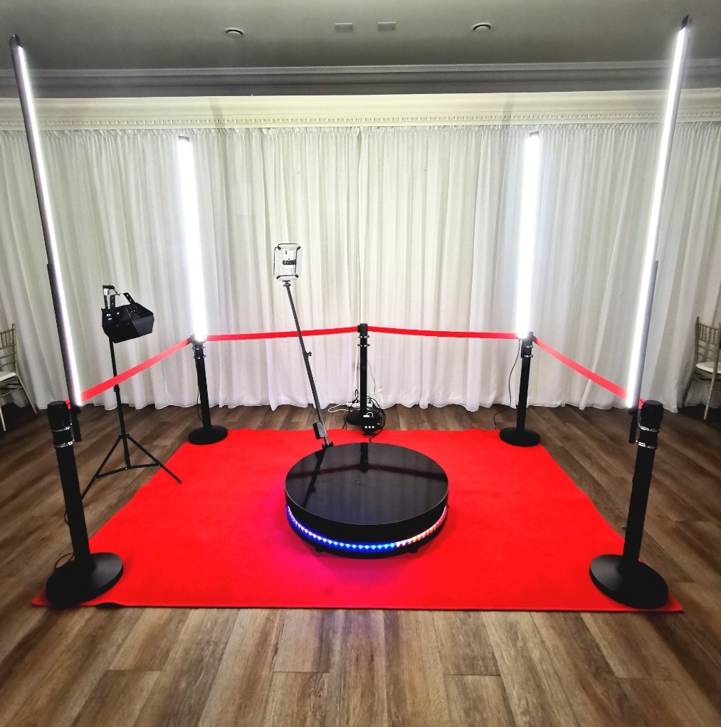 360 stopni fotobudka z oświetleniem LED i czerwonym dywanem, otoczona taśmą, gotowa do użycia na evencie, widok z przodu.
