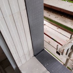 SLIMBUD Liubomyr Stefanko - Fragment muru z betonu komórkowego z zamontowanym ościeżem drzwiowym w trakcie montażu, widoczne rusztowanie z boku.