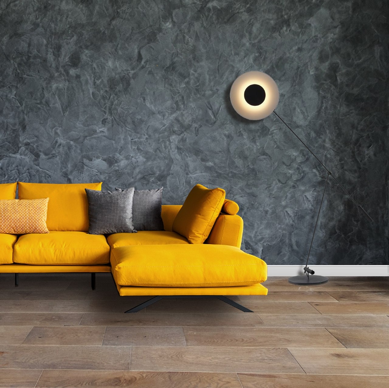 Żółty narożnik z poduszkami na tle szarej ściany z efektem dekoracyjnym i okrągłej lampy podłogowej.