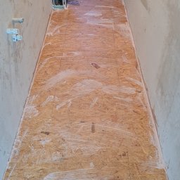 Radosław Kefer - Przygotowanie podłoża z płyt OSB w wąskim korytarzu, gruntowanie białą emulsją, ściany w stanie surowym.