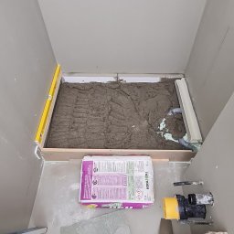 Radosław Kefer - Przygotowanie podłoża pod prysznic z wylewką i workiem kleju elastycznego KeraKoll Bez Limitu, widoczne narzędzia i poziomica.