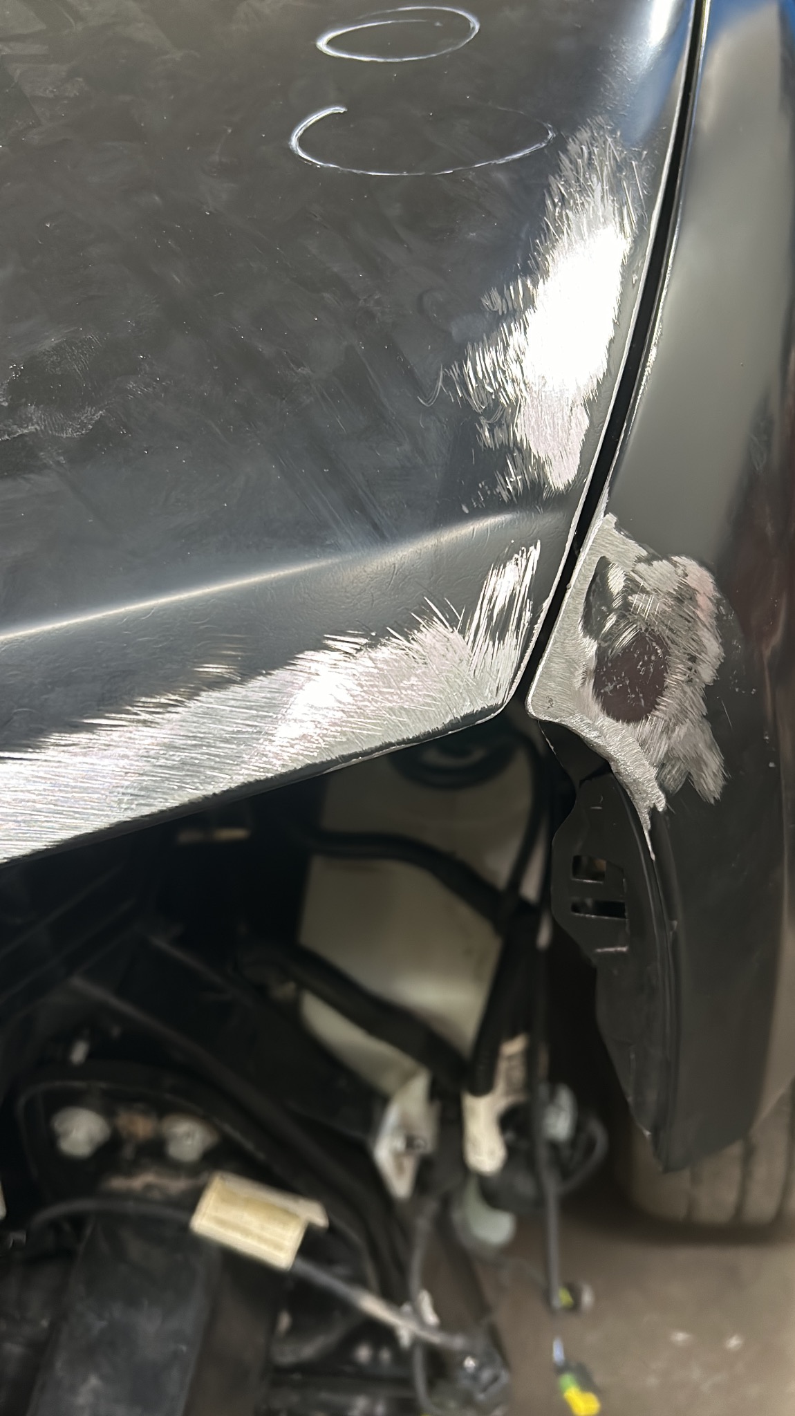 Przygotowanie powierzchni karoserii samochodu do lakierowania: zarysowane i zmatowione elementy błotnika przed nałożeniem podkładu.