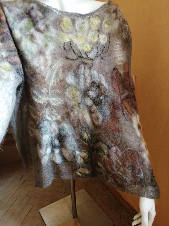 Beżowa tunika wełniana z aplikacjami kwiatowymi, prezentowana na manekinie na metalowym stojaku.